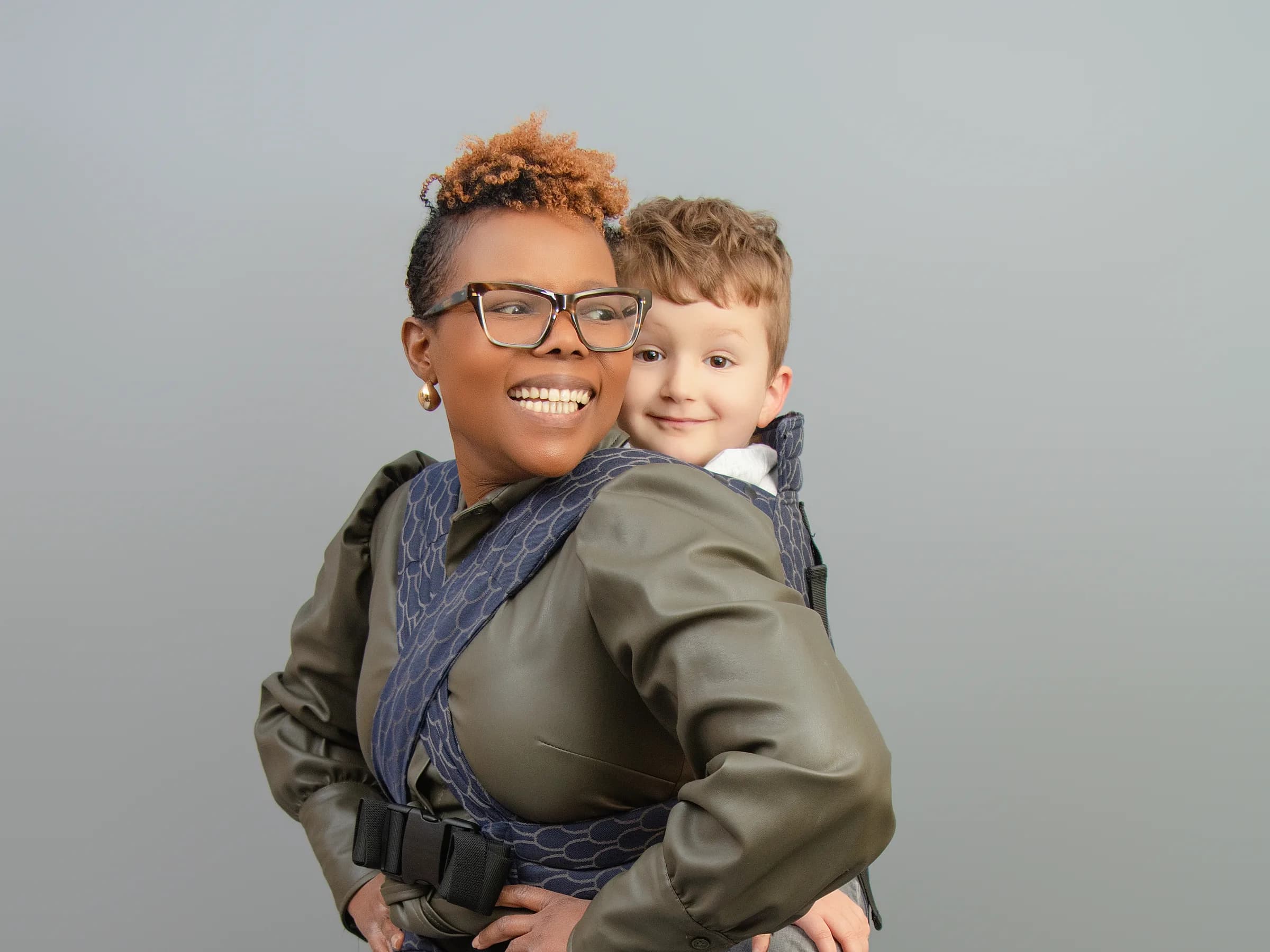 A parent back-carrying her toddler in a Babue carrier